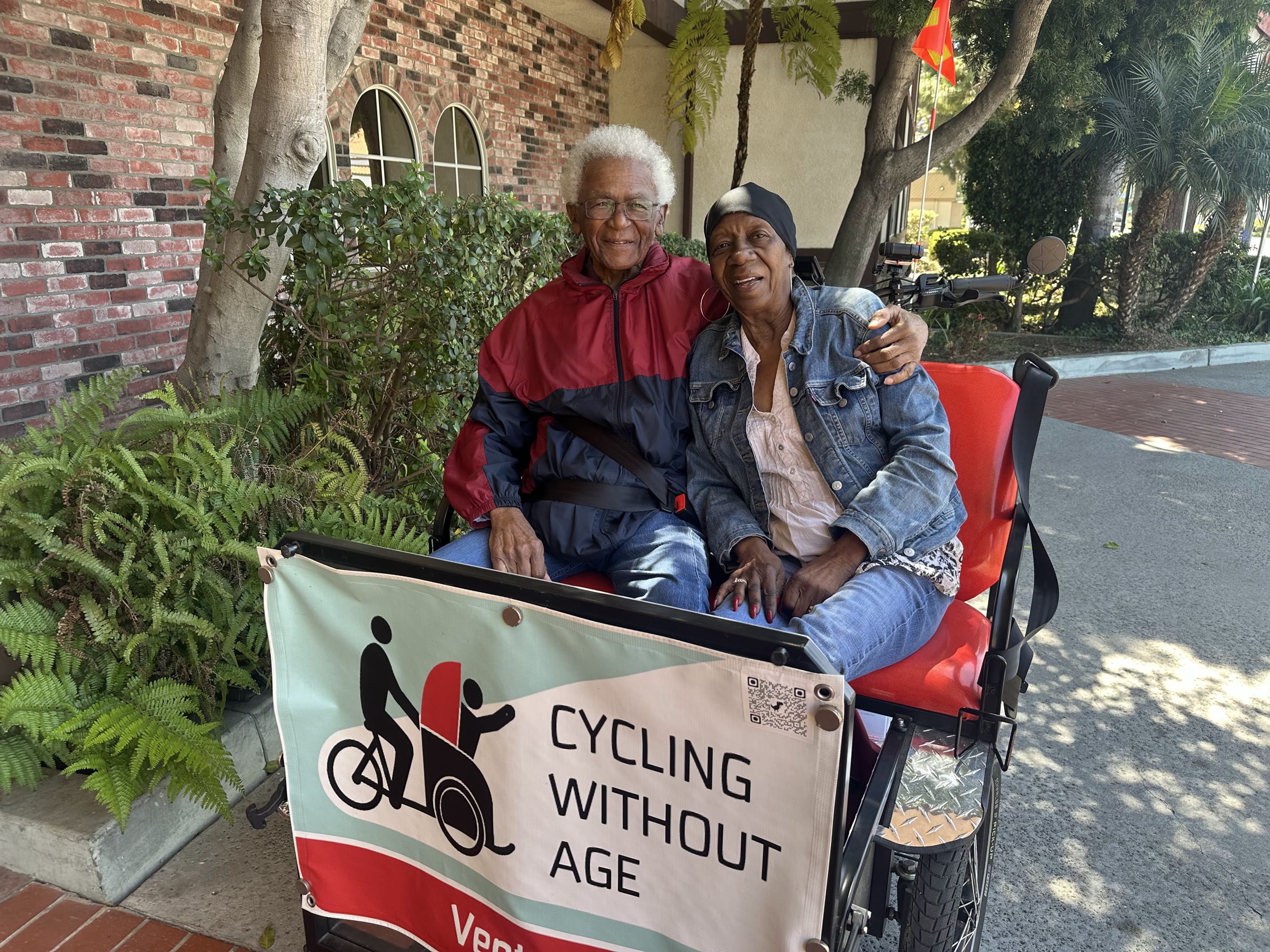 Smiling senior couple riding together in a Cycling Without Age Ventura trishaw